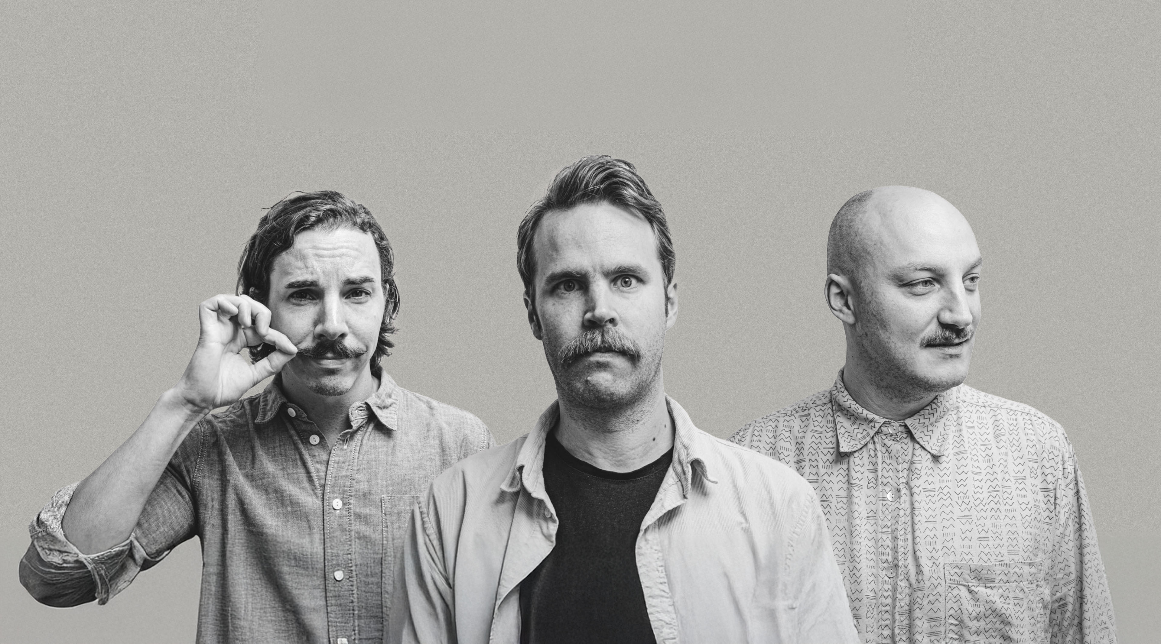 Tre menn med bart står ved siden av hverandre