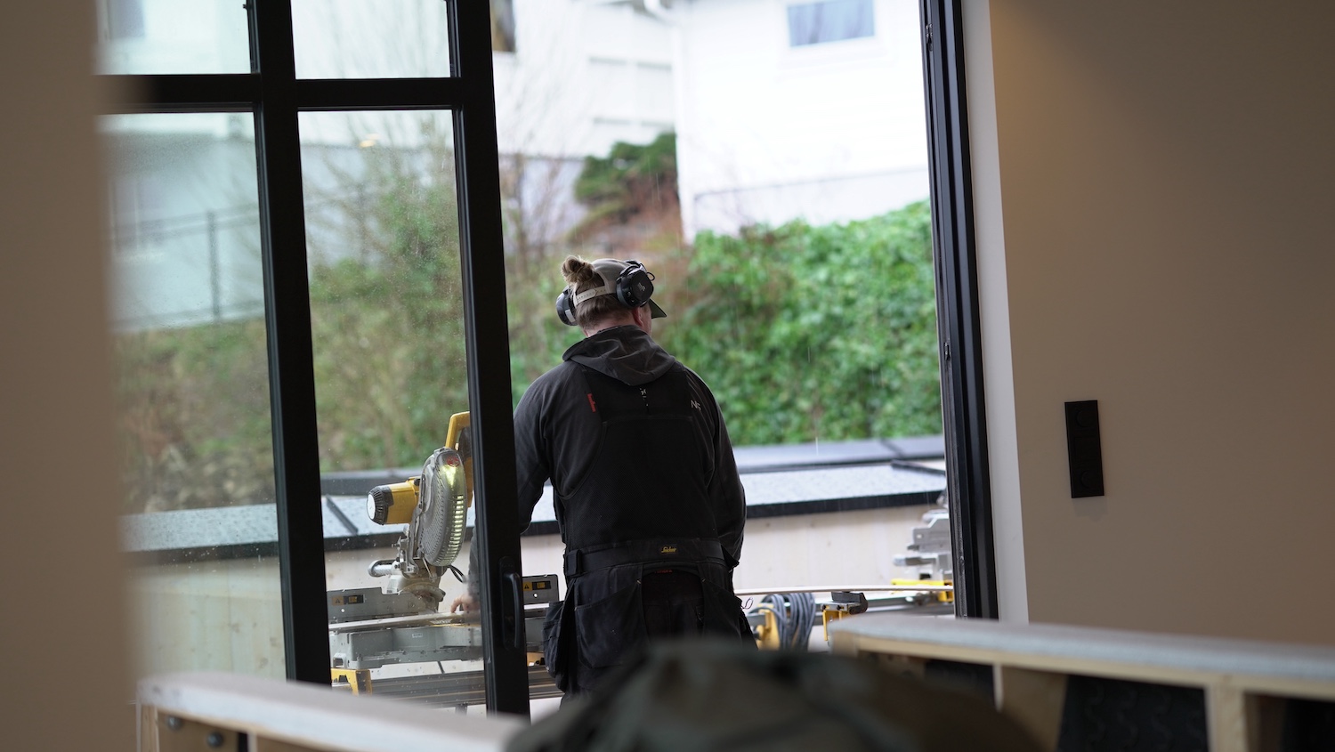 Tømrer med ryggen til kamera som bruker kappsag på treverk